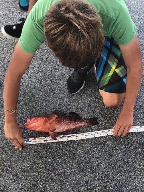 Youth measuring fishing catch.